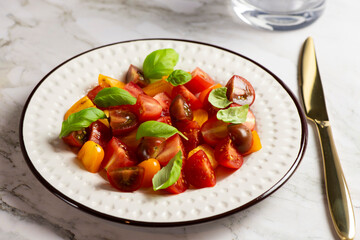 Salad with halves of red and yellow tomatoes cherry with basil