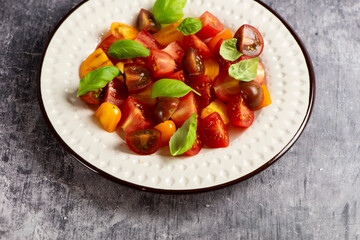 Salad with halves of red and yellow tomatoes cherry with basil