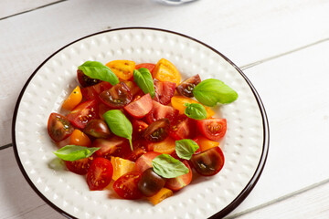 Salad with halves of red and yellow tomatoes cherry with basil