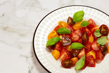 Salad with halves of red and yellow tomatoes cherry with basil