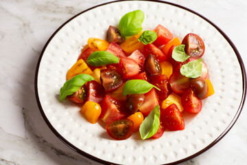 Salad with halves of red and yellow tomatoes cherry with basil