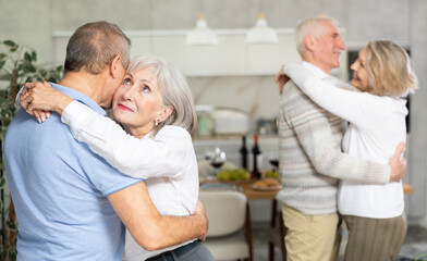 Fototapeta premium Couples of elderly women and men dancing in kitchen at home