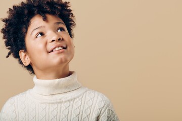 Young african american boy in a turtle neck sweater gazing upward with a look of wonder and curiosity in his eyes