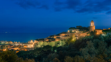 Fototapeta premium Blue hour over Castiglione della Pescaia, old town and sea. Maremma Tuscany, Italy