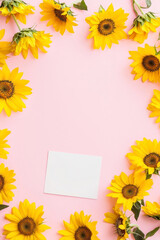 Obraz premium Vertical Sunflowers pink background. Festive holiday greeting card for Birthday, Woman or Mothers Day, blank copy paper and a greeting card. View from above.