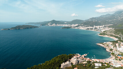Obraz premium Aerial view of St. Nicholas Island and Budva and Becici town from afar. The Adriatic coast in Montenegro. Clear turquoise water. A calm seascape. The resort is popular among tourists.