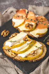 Two sandwiches with cheese, pear and nuts on a tray.