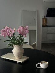 Minimalist Interior with Pink Lilies and Cappuccino Cup on Black Table