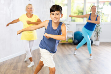 Active family three generations of mother, grandmother and teen son are learning sports Latin American dances in studio class. Joint pastime, active hobby