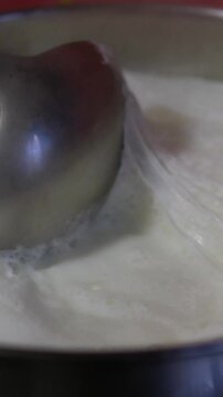 Milk boils and steams hot. Boiling milk in a stainless steel vessel. The milk is about to boil. Boiling milk flows from the pan onto the gas stove. Cow's milked boils in a kettle. 4K