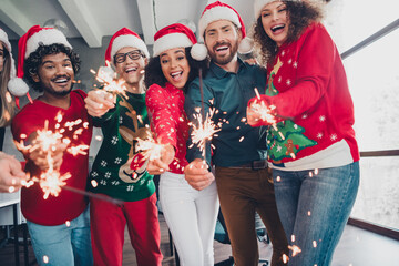 Photo of happy funny friendly colleagues friends dressed new year sweater celebrate corporate party xmas time indoors