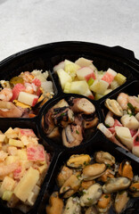 Finger food. Traditional seafood antipasti. Closeup view of a dish with different kinds of seafood preparations such as octopus, mussels with provencal, shrimps cocktail, pickles and kani kama salad