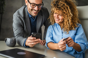 Adult man and woman colleagues buy online on mobile phone on break