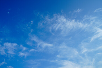 Serene and picturesque sky with scattered fluffy clouds under a bright blue atmosphere. Clear sky and sunlight create a peaceful and expansive view