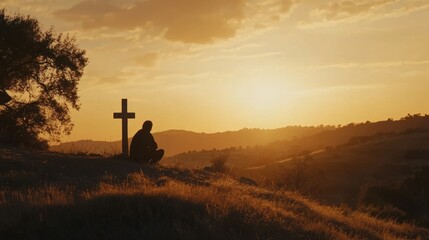 A person prays at a cross during a serene sunset in the hills