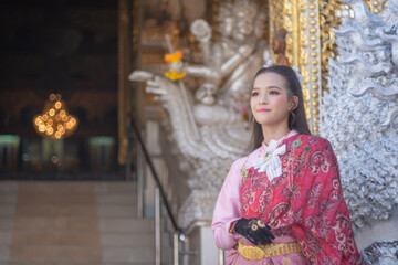 Beautiful Asian woman tourist wearing traditional Thai dress costume. The travel destination is Wat San Payang Luang Temple famous place of tourist attraction in Lamphun, Thailand. Portrait fashion.