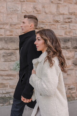 a joyful couple walking through a charming European city in winter. Wedding, love, street style