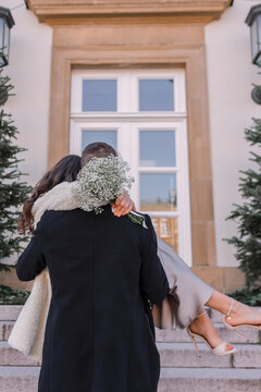 A happy man carrying his wife in his arms after their wedding