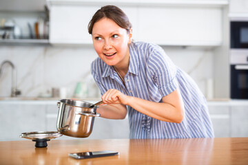 Portrait of a housewife preparing soup in a pot in the kitchen