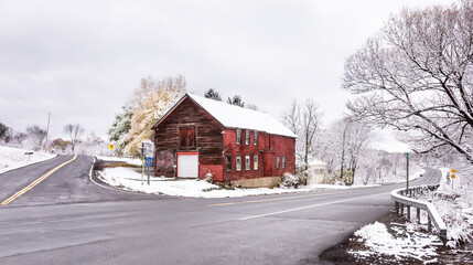 Red barn at snowy crossroads in winter