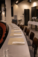 Tables set up for a meal with utensils and mats laid out for attendees in conference room
