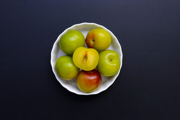 Fresh green plum fruit on dark background.