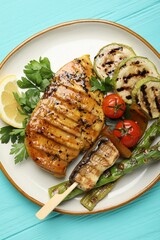 Delicious grilled vegetables and chicken breast on light blue wooden table, top view
