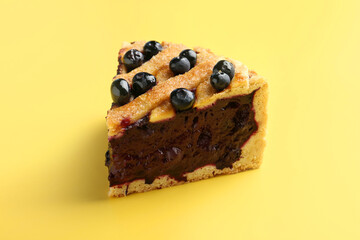 Slice of homemade blueberry pie on yellow background