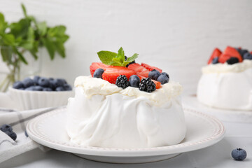 Pavlova cake (meringue dessert) with whipped cream, fresh berries and mint on white table, closeup