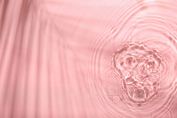 Fototapeta na wymiar Rippled surface of clear water on pink background, top view