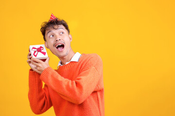 Surprised Asian Guy Holding Gift Box With Copy Space Isolated on Yellow Background