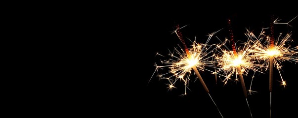 Beautiful sparklers lit at night outdoors, with space for text.