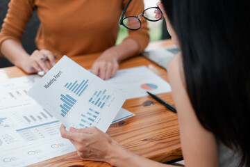 Two colleagues reviewing marketing data and charts at a wooden desk, focusing on business growth and strategy.