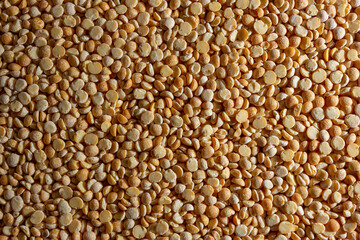 Uncooked Polished Split Peas Background. A Culinary Canvas of Dry Yellow Peas, Creating a Lively and Textured Background for Gourmet Cooking. Scattered Raw Polished Peas. Healthy Eating Ingredients