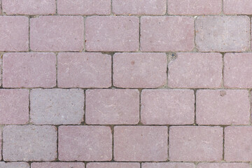 A brick wall with a pinkish color, decorative artificially aged paving slabs