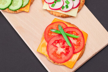 Different Cracker Sandwiches with Tomato, Cucumber, Radish and Cheese on Cutting Board. Easy Breakfast. Diet Food. Quick and Healthy Sandwiches. Crispbread with Tasty Filling. Healthy Dietary Snack