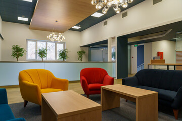 Modern lounge area with colorful seating, wooden tables, and greenery