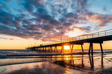 Fototapeta premium Silhouettes of people strolling along the Glenelg Beach jetty at sunset