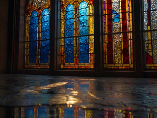 Obraz premium A window with stained glass patterns, creating colorful reflections on the floor as it opens.