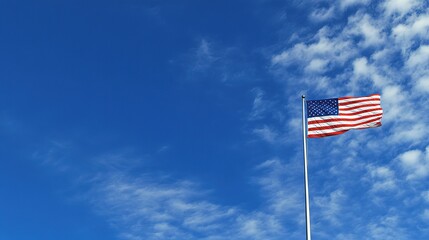 American flag waving against a bright blue sky with clouds.