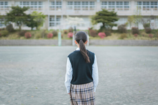 校舎を眺める女子生徒の後ろ姿
