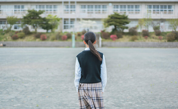 校舎を眺める女子生徒の後ろ姿