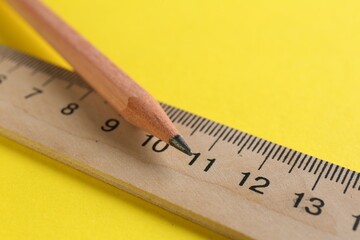 Ruler and pencil on yellow background, closeup