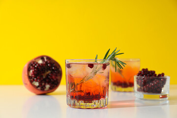 Red cocktail with fresh pomegranate on a yellow background