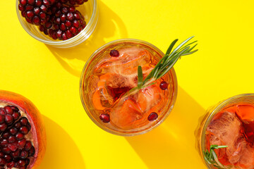 Red cocktail with fresh pomegranate on a yellow background