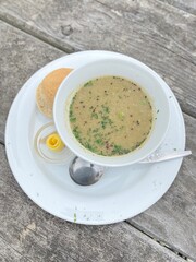 Cream of broccoli soup with bread on the white plate on the wooden table