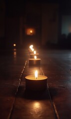 A line of candles with soft glow in a memorial hall, empty dark background