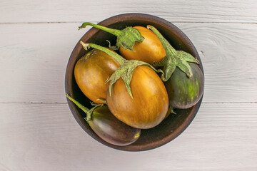 Fresh Harvest: Bowl of Ripe Eggplants on Rustic Wooden Surface