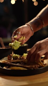 Chef agregando guacamole a Tacos de Aguja en Mexico, comida mexicana