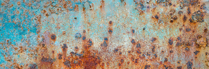 Close-up of a rusty metal surface featuring blue peeling paint, corrosion patterns, and textured decay.